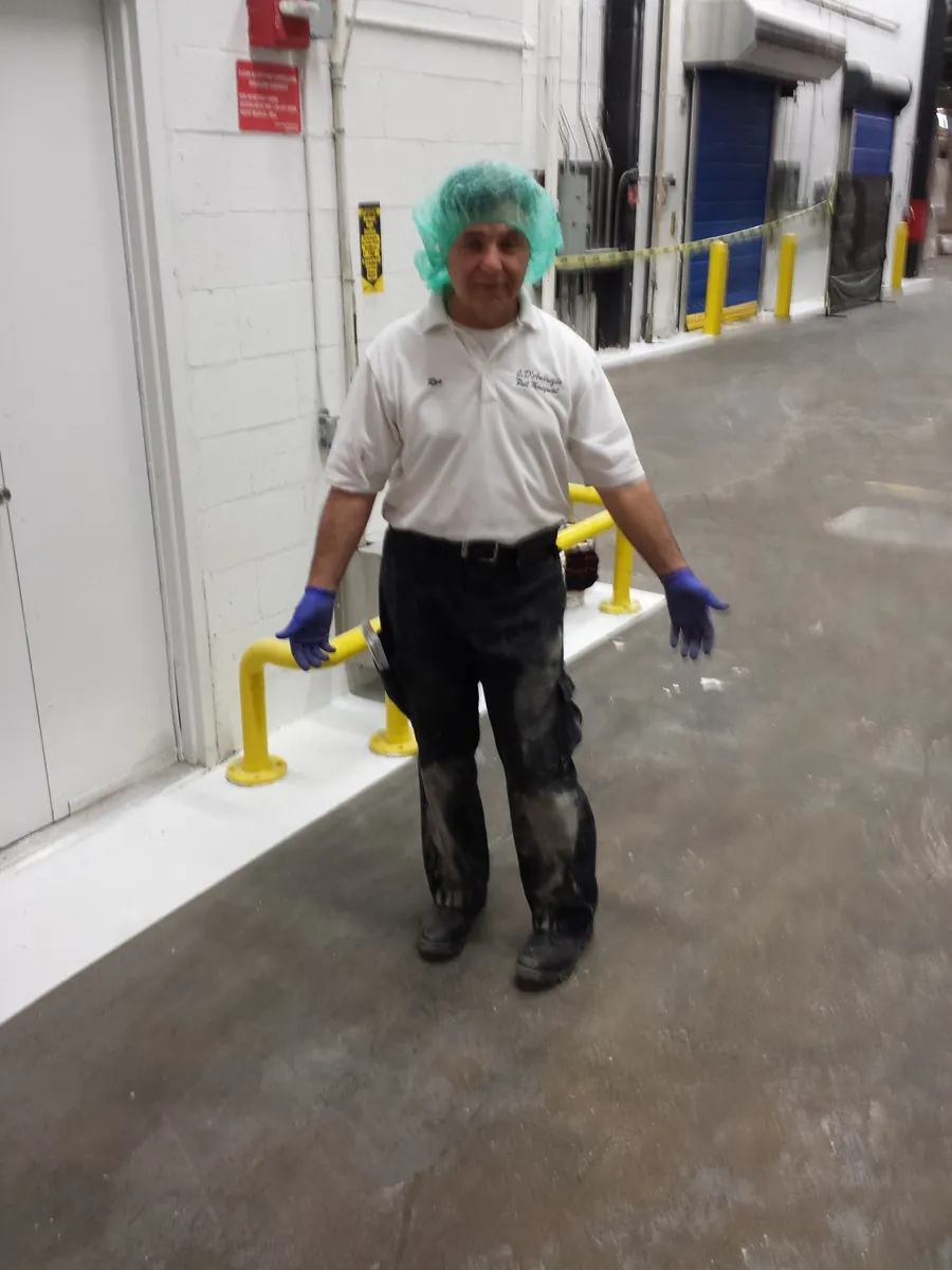 A Marrone technician in a hairnet walking a food facility corridor