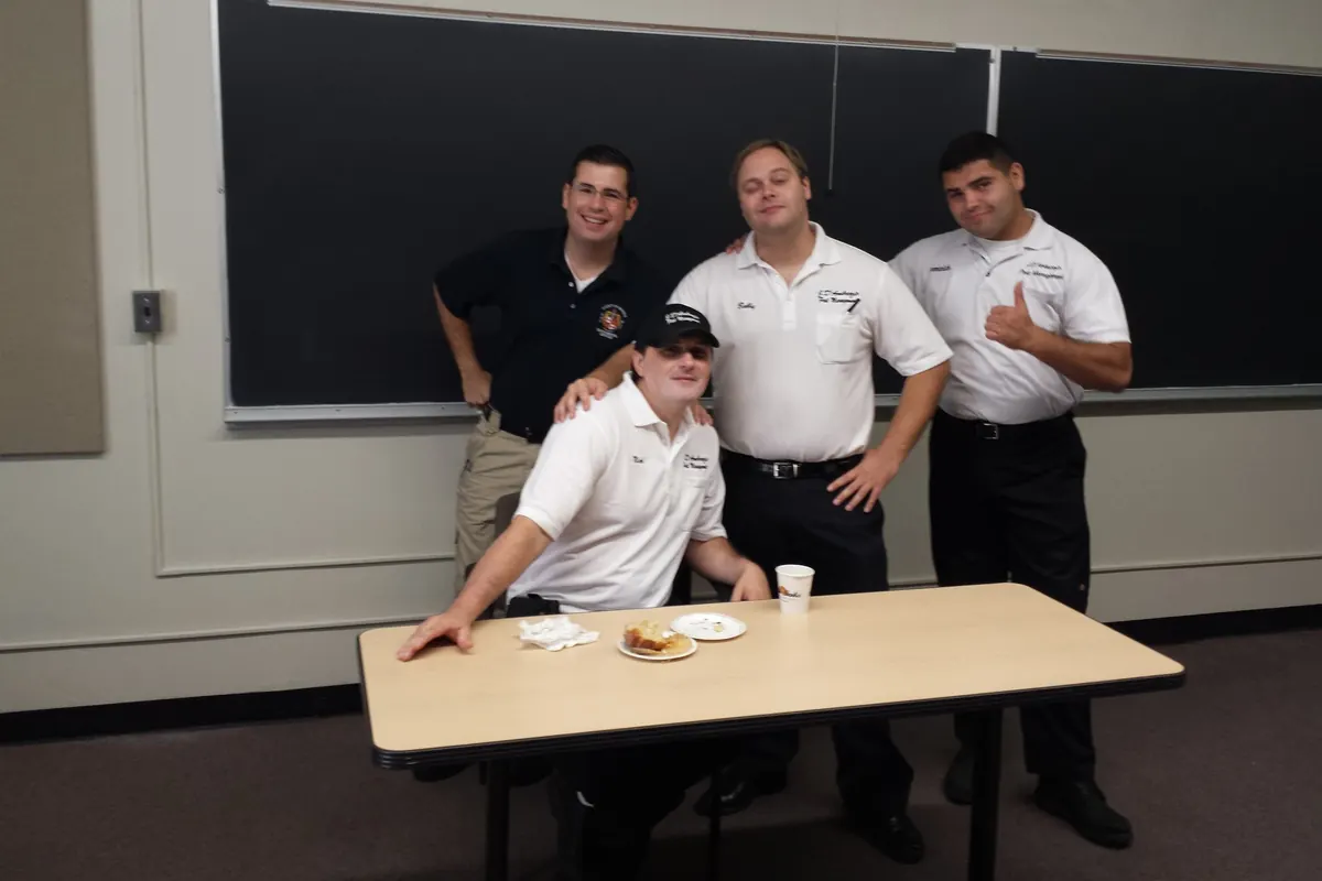 Four uniformed Marrone team members seated around a classroom table